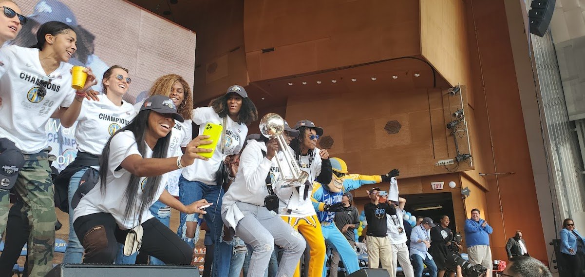 Celebrating Golden State Warriors championship with players, fans, and a trophy on stage.