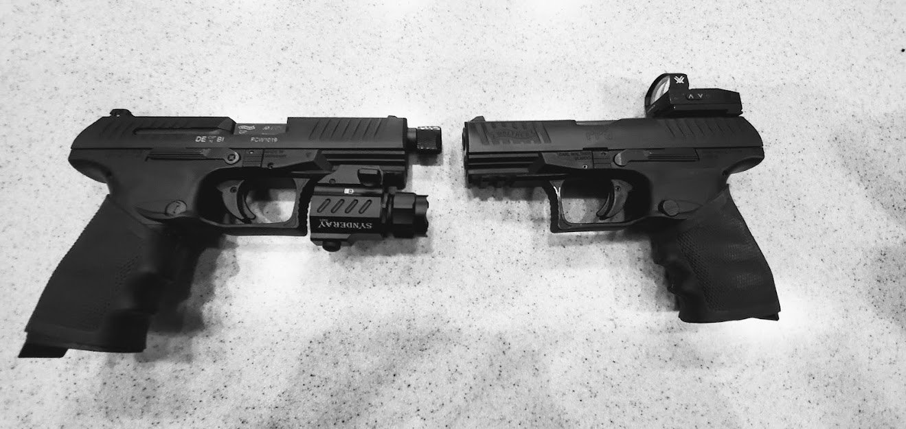 Two handguns facing each other on a speckled surface.