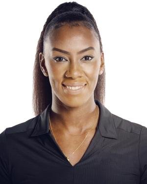Portrait of a woman with long dark hair pulled back, wearing a black collared shirt, smiling confidently against a plain background.