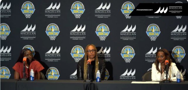 Three women sitting at a panel table during a press conference or event, with a backdrop featuring logos of SK Soccer, Magellan and related sponsors.