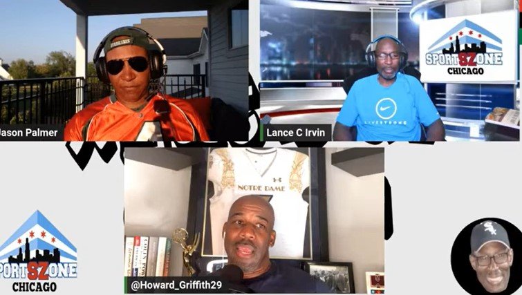 A screenshot of a virtual meeting with four men, each in separate video frames. One man is wearing sunglasses and an orange sports jersey, another is in a blue shirt with a Chicago sports zone logo, the third man has a Note Notre Dame poster behind him, and the fourth man is smiling wearing a black cap and glasses.